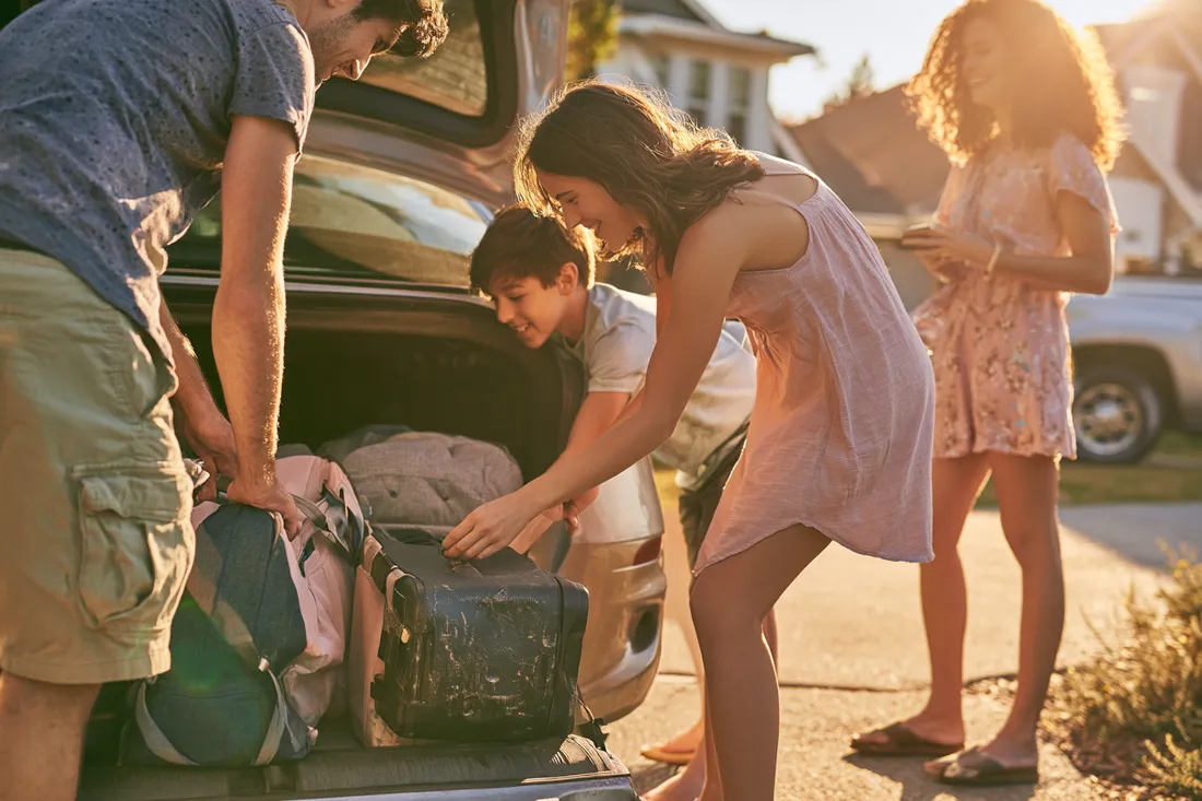 Family packing a car for a trip funded by a mid-size loan